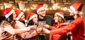 Young friends with santa hats celebrating Christmas with champagne wine toast at home reunion - Winter holidays concept Royalty Free Stock Photo