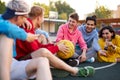 Young friends sitting on basketball court, relaxing and taking break after game