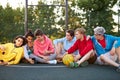 Young friends sitting on basketball court, relaxing and taking break after game