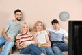 Young friends with snacks watching TV on sofa