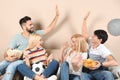 Young friends with snacks watching TV on sofa