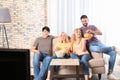 Young friends with snacks watching TV on sofa