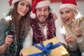 Young friends with sparklers and gift enjoying in party on Christmas day Royalty Free Stock Photo