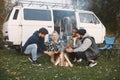 Young friends warming hands by fire at forest