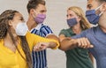 Young friends wearing face protective mask doing new social distancing greet with elbows bumps for preventing corona virus spread Royalty Free Stock Photo