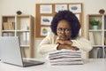 Young frowning busy african american woman employee sitting at office table