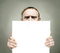 Young frowning man holding blank sign paper