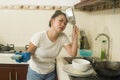 Young frustrated Asian woman in domestic chores stress - beautiful overwhelmed and stressed Japanese girl washing dishes in Royalty Free Stock Photo