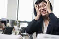 Young frustrated businesswoman sitting at desk with head in hands Royalty Free Stock Photo