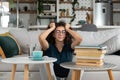 Young frustrated school girl sitting on floor with pile of books feeling sad that she need to read. Female first year college