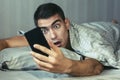 Young frustrated and stressed man is late. He is waking up, looking at smartphone and is shocked. The concept of a modern rhythm o Royalty Free Stock Photo