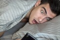 Young frustrated and stressed man is late. He is waking up, looking at smartphone and is shocked. The concept of a modern rhythm o Royalty Free Stock Photo