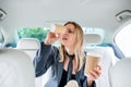 Young frustrated woman with empty paper glasses sitting in car.