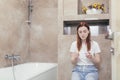 Young frustrated woman looking at a quick positive or negative result pregnancy test sitting in bathroom by a unwanted. Female Royalty Free Stock Photo