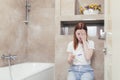 Young frustrated woman looking at a quick positive or negative result pregnancy test sitting in bathroom by a unwanted. Female Royalty Free Stock Photo