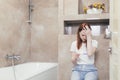 Young frustrated woman looking at a quick positive or negative result pregnancy test sitting in bathroom by a unwanted. Female Royalty Free Stock Photo