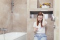 Young frustrated woman looking at a quick positive or negative result pregnancy test sitting in bathroom by a unwanted. Royalty Free Stock Photo