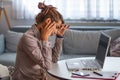 Young frustrated woman working at office desk in front of laptop suffering from chronic daily headaches, treatment online, Royalty Free Stock Photo