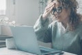 Young frustrated woman working at office desk in front of laptop suffering from chronic daily headaches, treatment online, Royalty Free Stock Photo