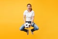 Young fun expressive European woman football fan jumping in air, cheer up support team, holding soccer ball isolated on Royalty Free Stock Photo