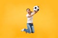 Young fun expressive European woman football fan jumping in air, cheer up support team, holding soccer ball isolated on Royalty Free Stock Photo