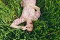 Young fun overjoyed beautiful woman in light patterned dress lying on grass showing victory sign resting in sunny Royalty Free Stock Photo