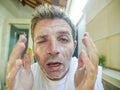 Young funny and attractive Caucasian man with itchy eyes at home bathroom washing his face with exfoliant soap looking at himself Royalty Free Stock Photo