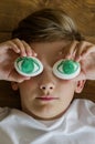 Young funny boy holding two organic eggs in front of his eyes. Emotions