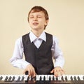 Young funny boy in a suit playing electronic synthesizer Royalty Free Stock Photo