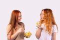 Young funny caucasian two women holding potato chips, Fast food banner concept. Redhaired girl sticking tongue out happy Royalty Free Stock Photo