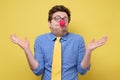 Young funny clown man with red nose and yellow tie showing ignorance Royalty Free Stock Photo