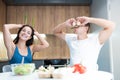 Young funny couple cooking breakfast in the kitchen man closes his eyes with mushrooms while his beloved wife holds