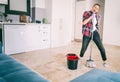 Young funny crazy charming girl woman cleans her apartment with a mop and have fun. House Hygiene and Cleaning Service Concept