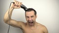 The man shaves his head and shouts loudly while looking in the mirror. Royalty Free Stock Photo