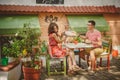 Young funny happy loving couple sitting at street open-air cafe and fighting with pillows outdoors. Pillow fight. Royalty Free Stock Photo