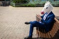 Young funny man in elegant suit sits on the bench on the city street Royalty Free Stock Photo