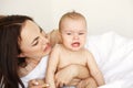 Young funny mom playing the ape her baby crying lying in bed at home. Royalty Free Stock Photo