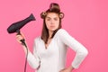 Young funny woman with hair dryer and rollers. Woman with hair dryer. Beautiful girl with straight hair drying hair with Royalty Free Stock Photo