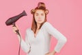 Young funny woman with hair dryer and rollers. Woman with hair dryer. Beautiful girl with straight hair drying hair with Royalty Free Stock Photo