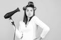 Young funny woman with hair dryer and rollers. Woman with hair dryer. Beautiful girl with straight hair drying hair with Royalty Free Stock Photo