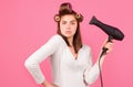 Young funny woman with hair dryer and rollers. Woman with hair dryer. Beautiful girl with straight hair drying hair with Royalty Free Stock Photo