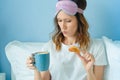 Young funny woman having a breakfast on the bed with cup of coffee and croissant Royalty Free Stock Photo