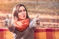 Young funny woman with thumbs up on a bench in an autumn park