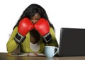 Young furious and angry afro american business woman in boxing gloves stressed by office computer desk work and negotiation fights Royalty Free Stock Photo