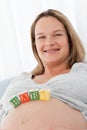 Young future mom with baby letters on her belly