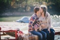 Young future parents and their dog in a funny costume sitting on a wooden bridge and having picnic near lake Royalty Free Stock Photo