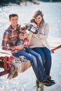 Young future parents and their dog in a funny costume sitting on a wooden bridge and having picnic near lake Royalty Free Stock Photo