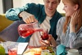 Gallant man pours sweet juice into glasses for women, treats them Royalty Free Stock Photo