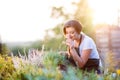 Young gardener in garden smelling flower, sunny nature