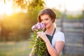 Young gardener in her garden smelling flowers, sunny nature Royalty Free Stock Photo